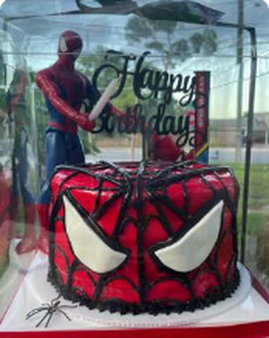 Red and black Spider-Man themed birthday cake with fondant eyes and web design