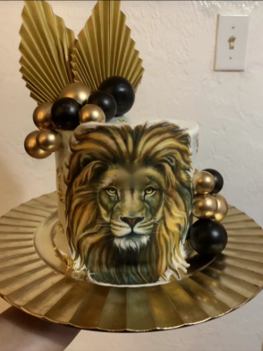 Hand-painted lion face cake with gold and black balloon cluster