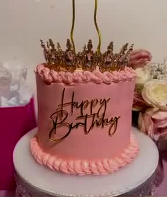 Pink buttercream birthday cake with gold crown topper and script lettering
