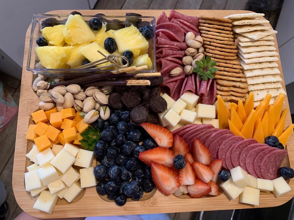 Charcuterie grazing board with meats, cheeses, fruit, pistachios, and crackers