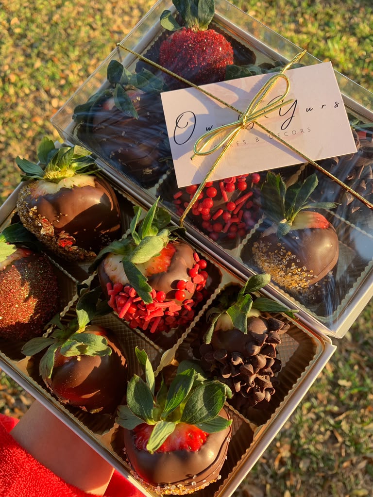 Chocolate covered strawberries finished with red glitter, sprinkles, and gold sugar in a branded gift box